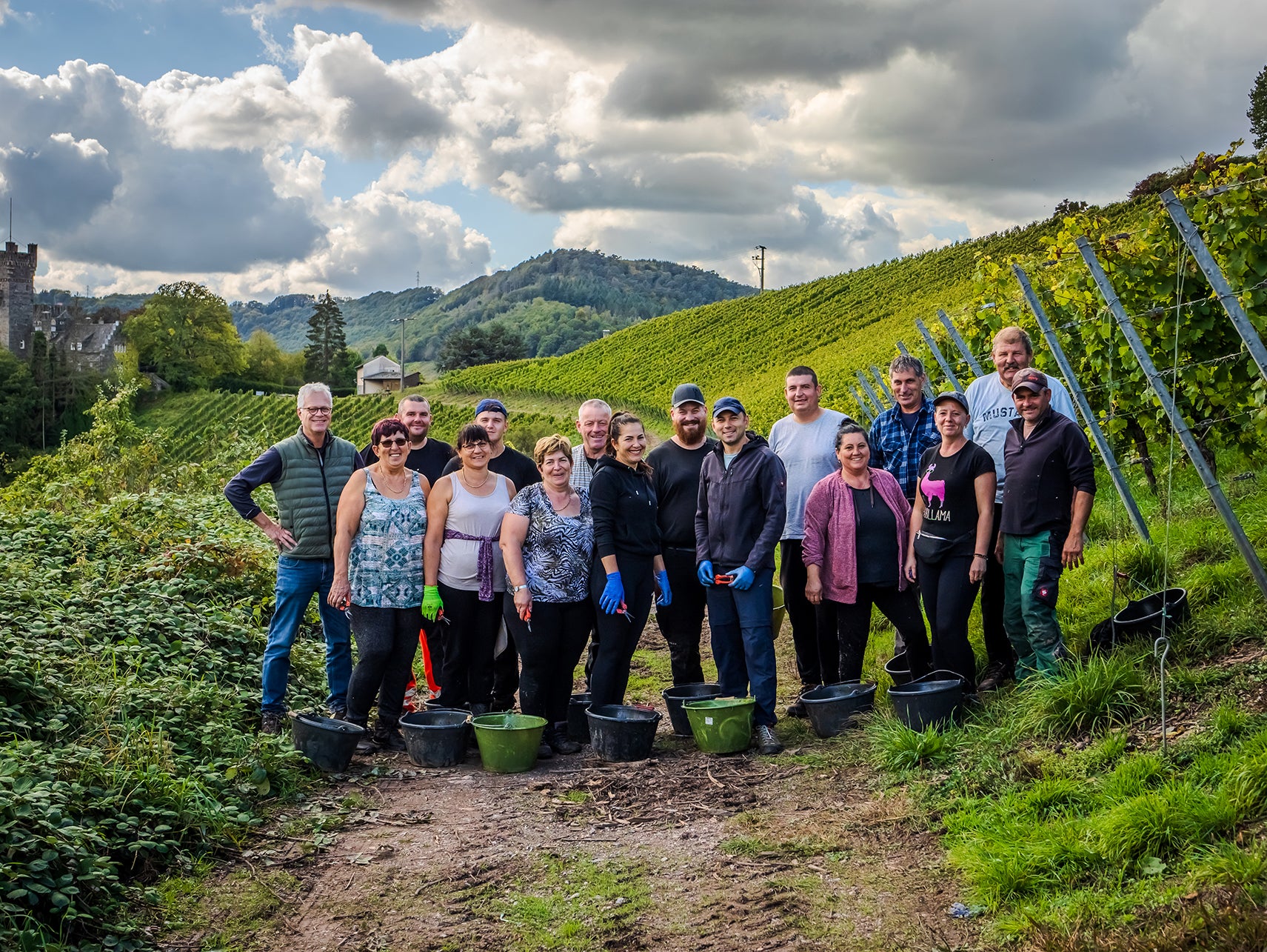 Gruppenbild des gesamten Teams in den Weinbergen mit Eimern und Werkzeug